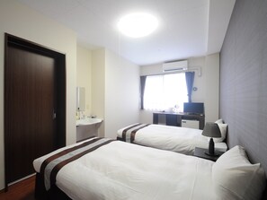 Een hotelkamer met twee bedden, een bureau, een flatscreen televisie, een raam met gordijnen en een airconditioning.