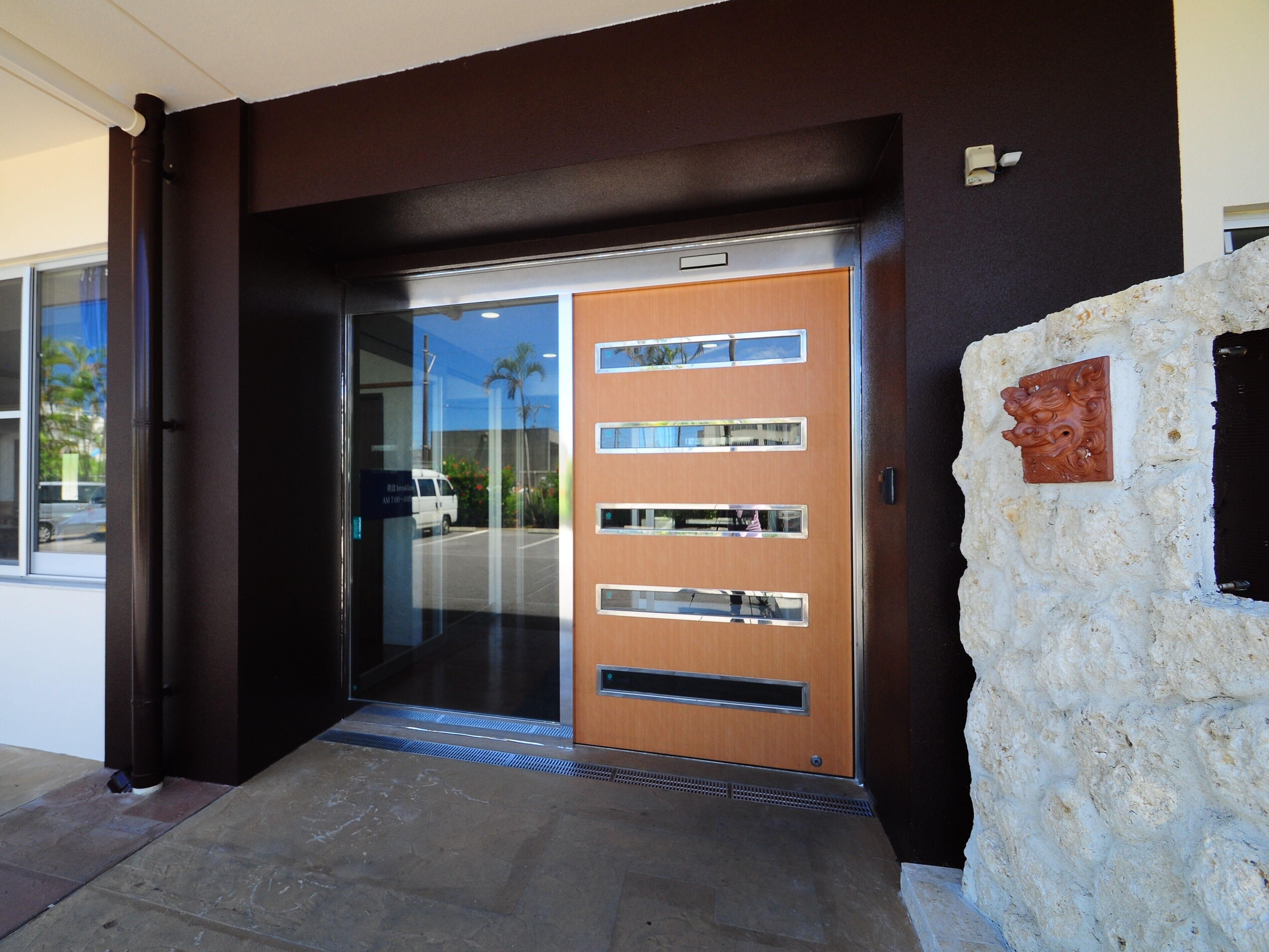 A modern building entrance with a glass door, a stone wall, and a metal door frame.