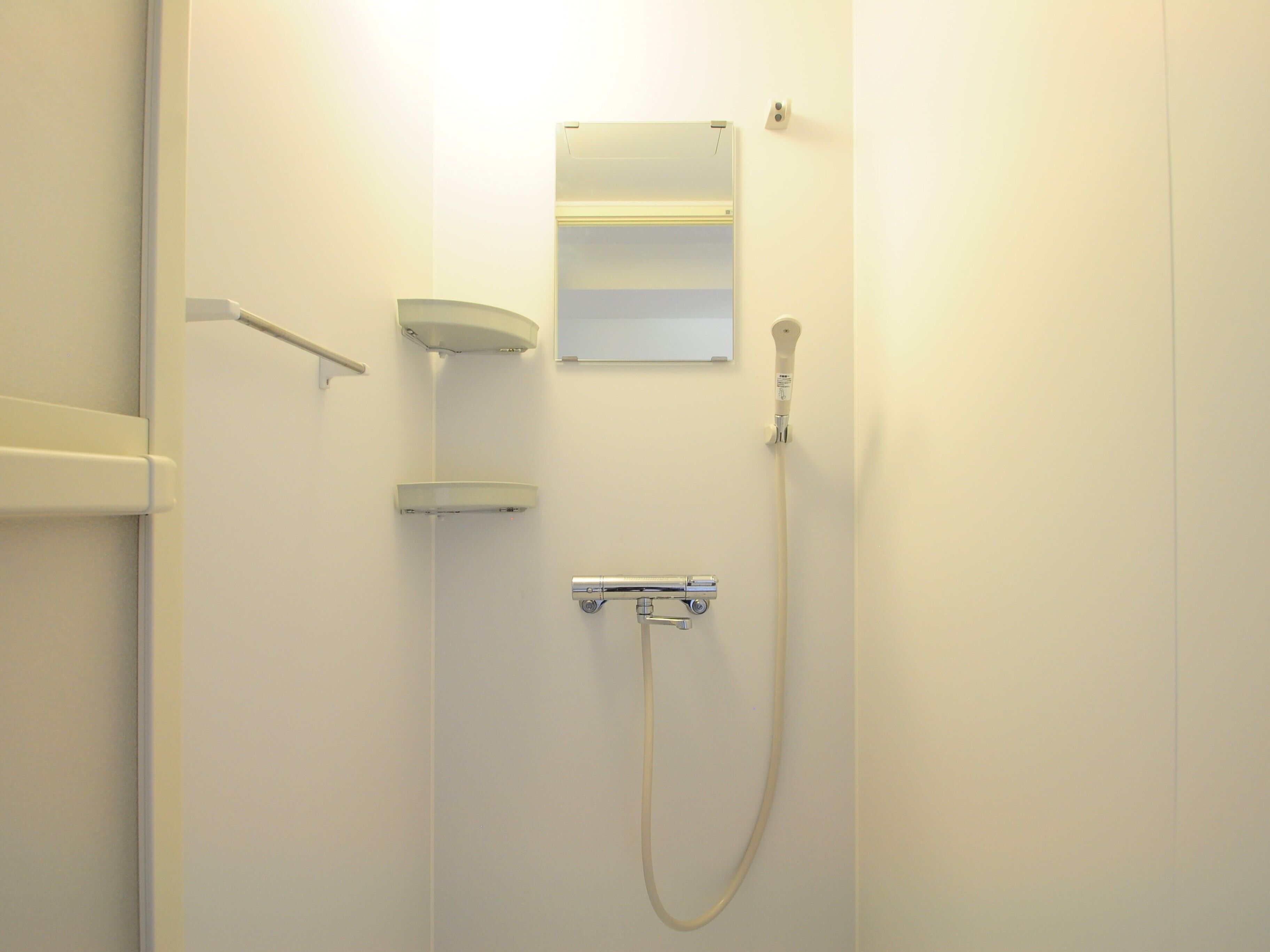A bathroom with a shower, a towel rack, and a mirror.