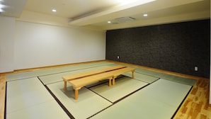 A room with tatami flooring, a wooden bench, and a dark accent wall.