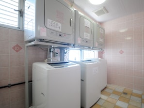 A laundry room with two front-loading washing machines and a metal shelf above them.