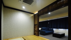 A room with a wooden table, a sofa, and a dark-colored couch.