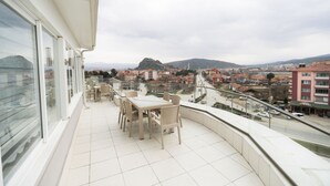 A balcony with a table and chairs, overlooking a cityscape with buildings and a hill. - Grand Dost Hotel (Osmancik)