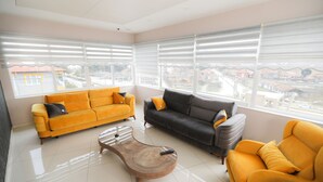 A modern living room with two sofas, one yellow and one gray, and a wooden coffee table. - Grand Dost Hotel (Osmancik)