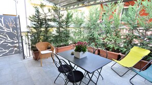 A patio area with a table and chairs, surrounded by potted plants and a decorative wall. - Via Cavour Appartamenti (Alba)