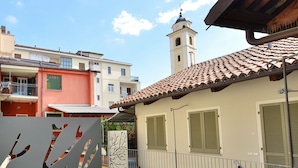 A residential building with a tiled roof, a balcony with metal railings, and a tower with a dome. - Via Cavour Appartamenti (Alba)