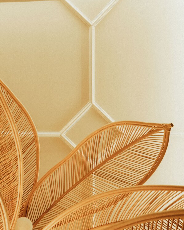 A close-up of a woven chair with a geometric wall pattern in the background.