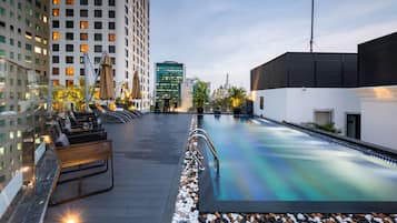 Alberca al aire libre, sombrillas en la alberca y camastros