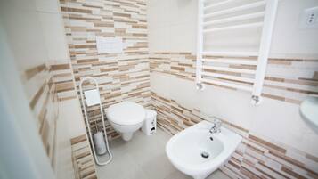 Un baño pequeño y moderno con inodoro, bidé y lavamanos.