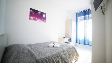 Un dormitorio con cama, un cartel con noche estrellada, cómoda y televisor montado en la pared.