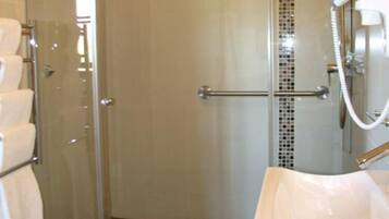 A modern bathroom with a glass shower enclosure, a white sink, and a tiled shower area.