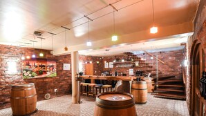 A rustic bar area with wooden barrels, brick walls, and a staircase leading to a loft. - Lovane Boutique Wine Estate & Guesthouse (Stellenbosch)