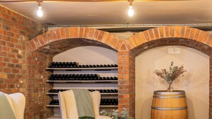 A cozy wine cellar with brick walls, wine racks, comfortable seating, and a large wooden barrel. - Lovane Boutique Wine Estate & Guesthouse (Stellenbosch)