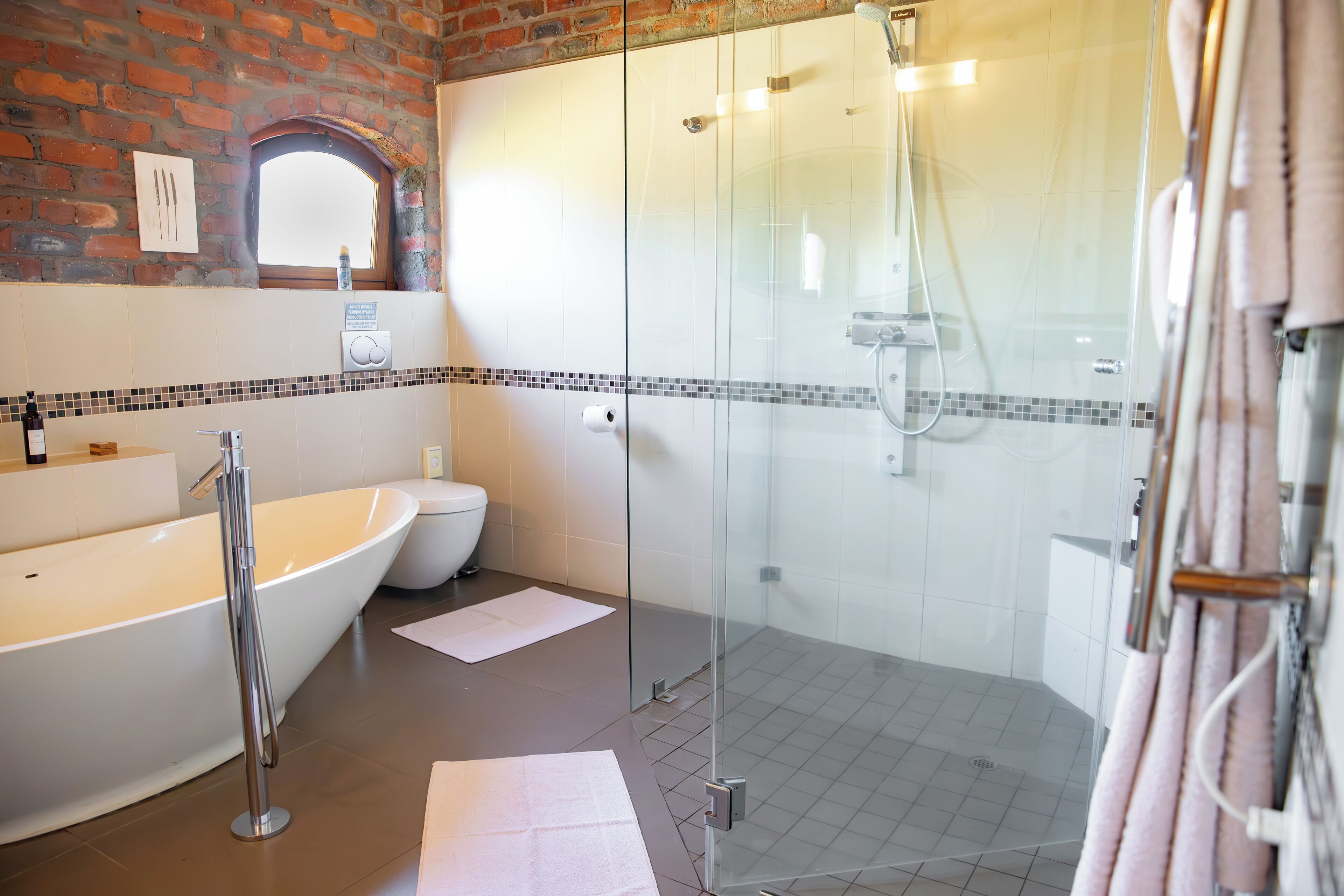 A modern bathroom with a freestanding bathtub, a glass-enclosed shower, and a white toilet.