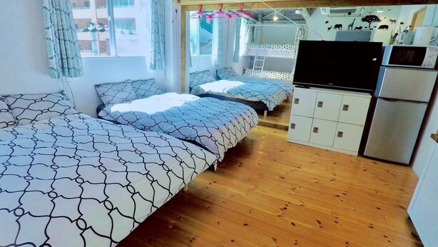 A compact room with two beds, a kitchenette, and a window with curtains. - Osaka guesthouse RELASTAY (Osaka)