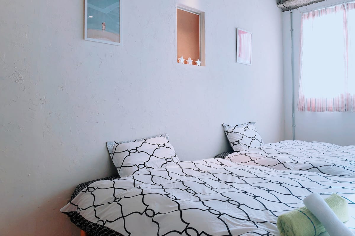A bedroom with a bed, pillows, and a window.