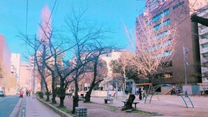 A city street with a pedestrian walkway, trees, benches, and playground equipment. - Osaka guesthouse RELASTAY (Osaka)