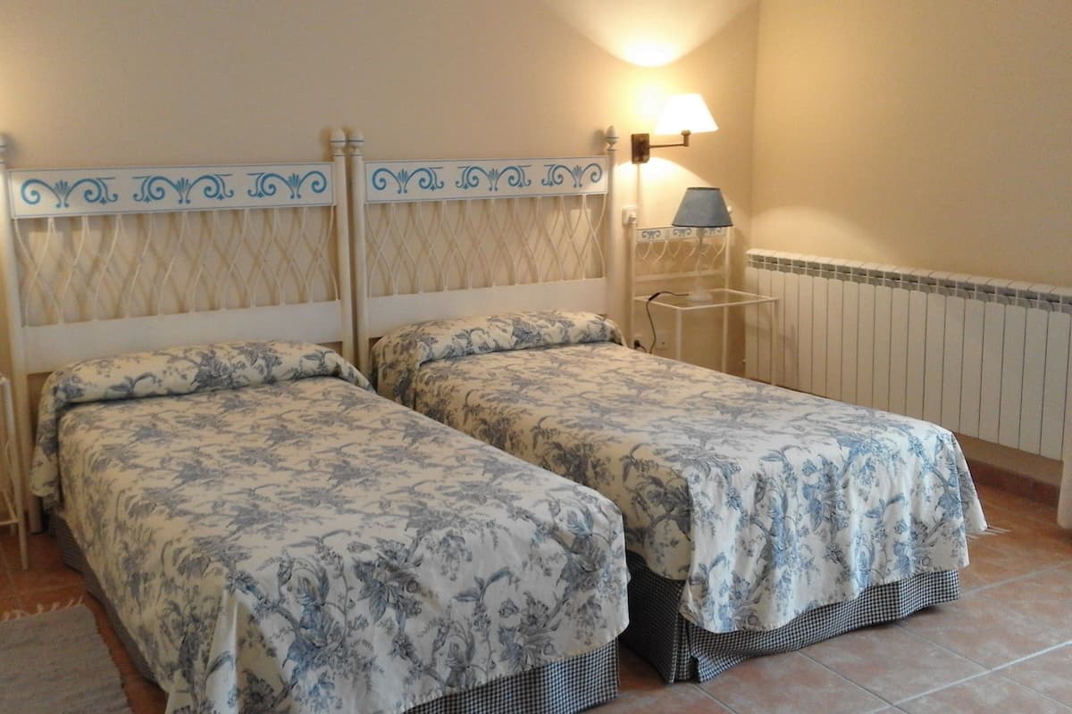 Habitación doble con dos camas, cada una con cabecero y lámparas de noche.