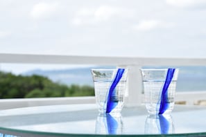 Deux verres d’eau sur une table en verre, avec une vue sur les montagnes en arrière-plan.
