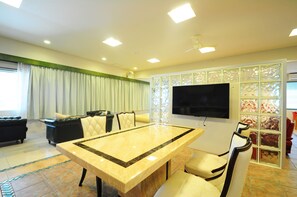 A modern living room with a large TV, a dining table, and a seating area. - Kaiho Fusaki main building (Ishigaki)