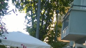 Un espace patio avec des sièges d’extérieur, un parasol blanc et une entrée avec une porte vitrée.