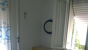 Une chambre à coucher avec un lit, une petite table de chevet, un miroir et une fenêtre avec des rideaux.