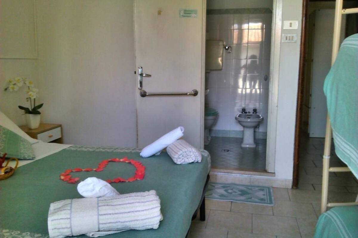 A hotel room with a bed, a bathroom with a toilet and bidet, and a shower area.