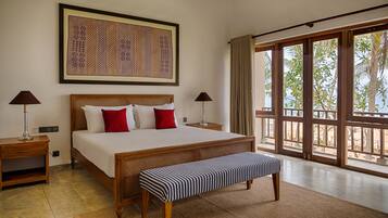 A hotel room with a large bed, two bedside tables, a bench, a large window with a view, and a framed artwork on the wall.