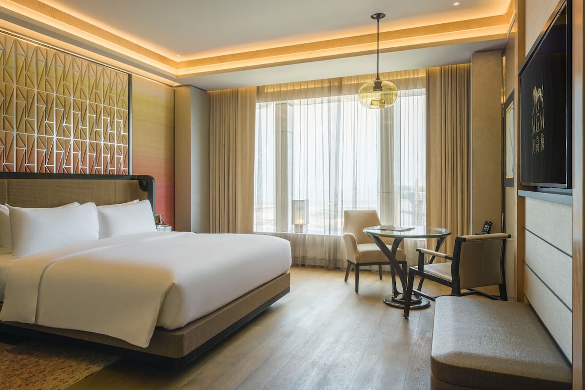 A hotel room with a large bed, a desk, and a chair.