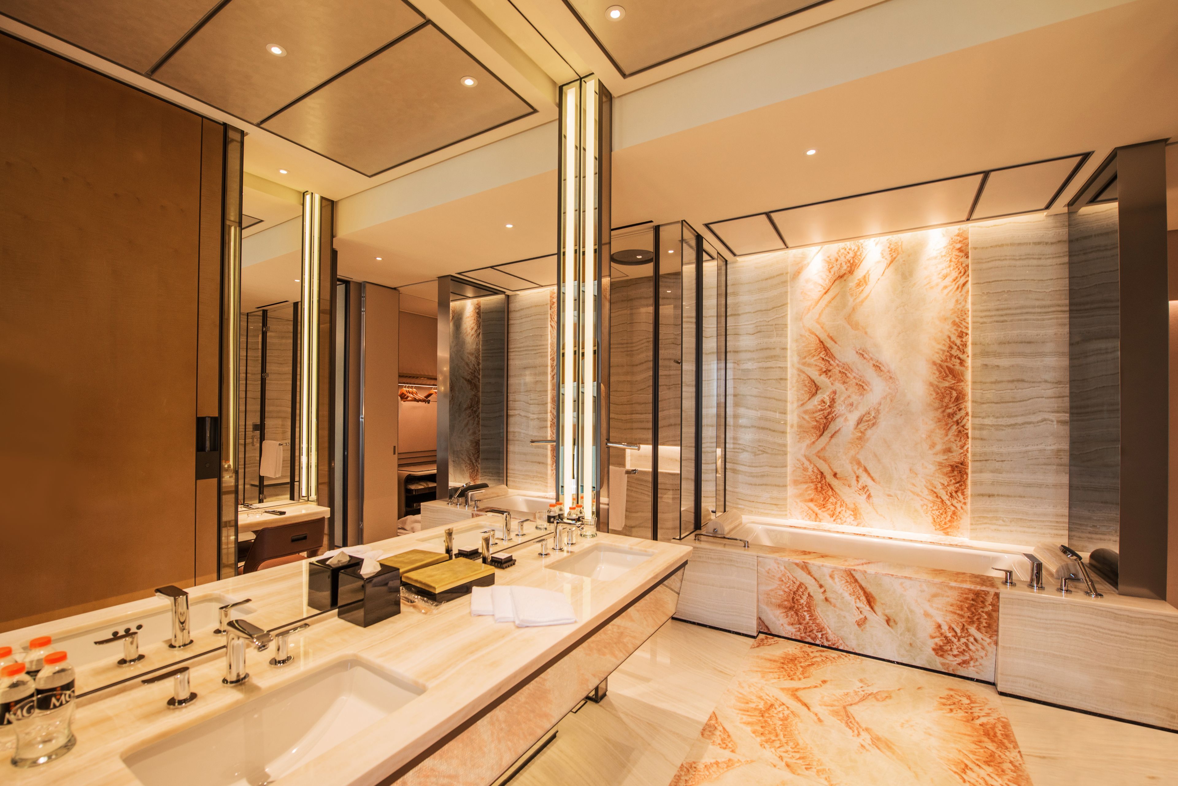 Un baño moderno con un espejo grande, dos lavamanos y una zona de ducha de mármol.