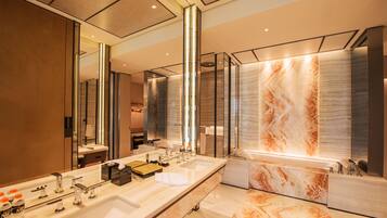 Un baño moderno con un espejo grande, dos lavamanos y una zona de ducha de mármol.