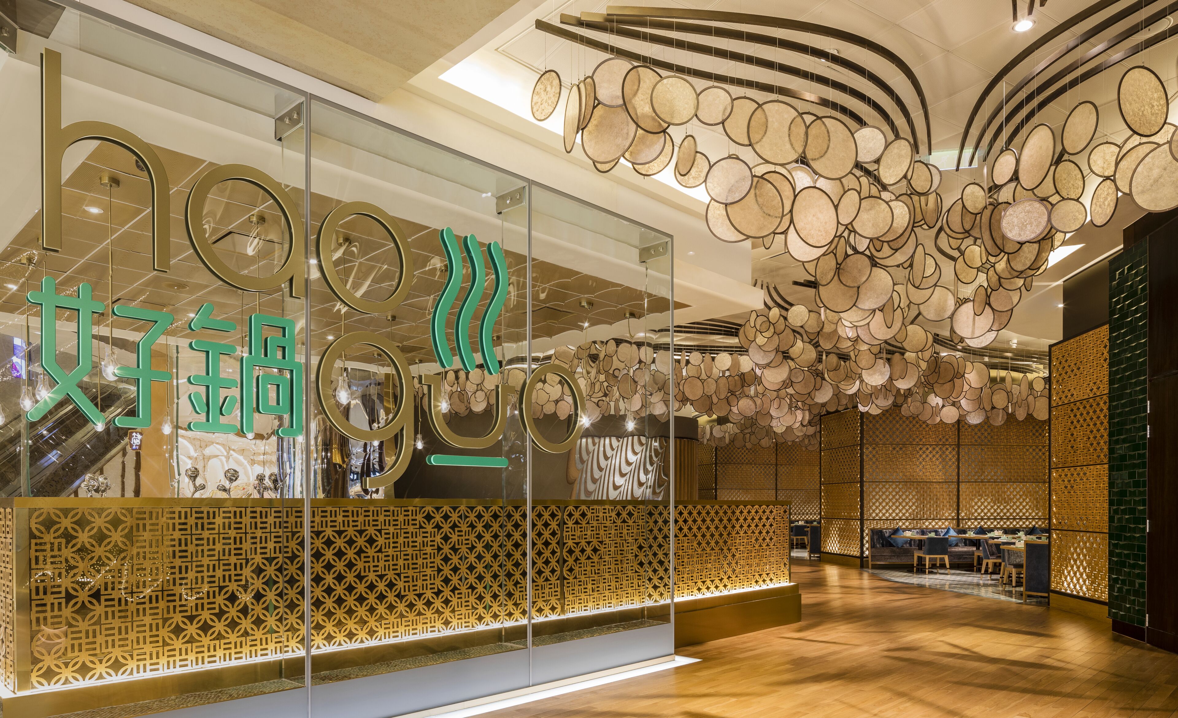 Ein modernes Interieur mit Glasfassade, geometrischen Wandmustern und einer Decke mit runden Leuchten.