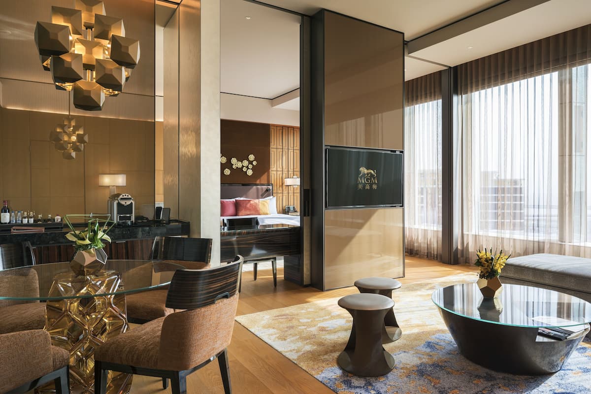 A modern living room with a glass coffee table, a sofa, and a dining area with a glass table and chairs.