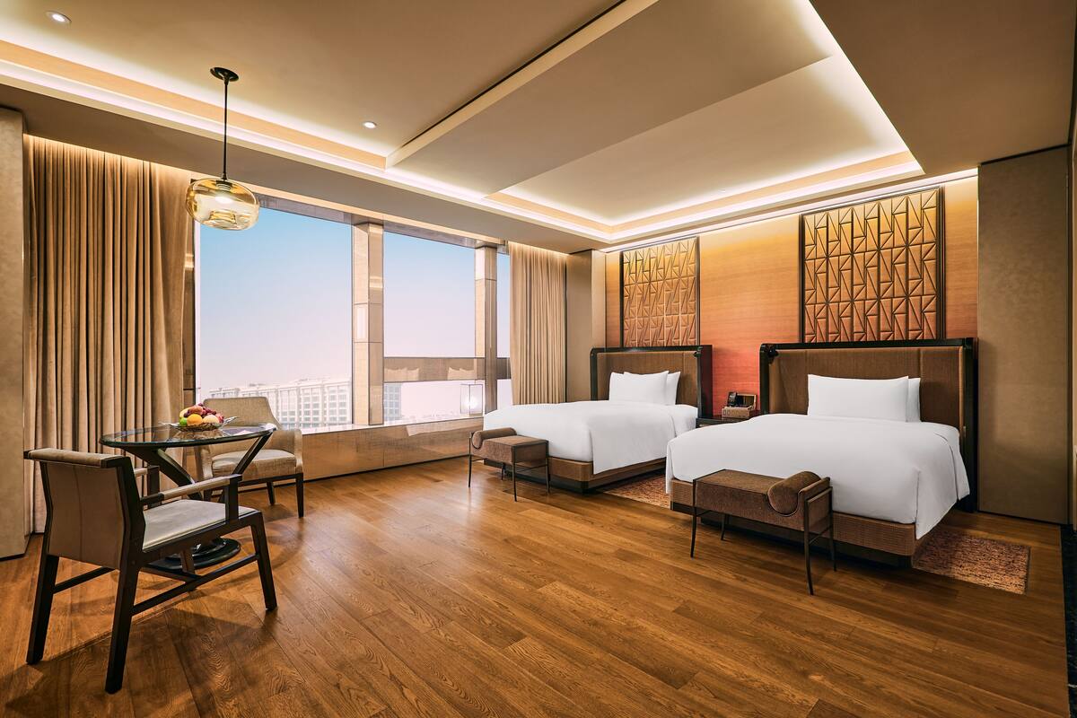 A hotel room with two beds, a desk, and a chair.
