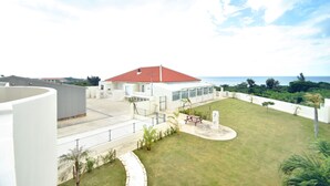 En boligejendom med et hus med rødt tag, en overdækket terrasse og havudsigt.