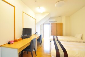 Une chambre d’hôtel avec un bureau en bois, une télévision, deux lits et une armoire.