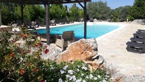 A pool area with lounge chairs and a pergola. - Agriturismo Grotta di Figazzano (Ostuni)
