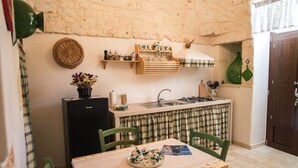 A compact kitchen with a black refrigerator, a sink, and a small dining area with a table and chairs. - Agriturismo Grotta di Figazzano (Ostuni)