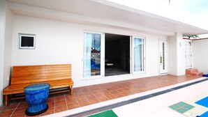 A modern building with a wooden bench, large sliding glass doors, and a tiled floor. - Hotel Kaiho Shishinomori (Ishigaki)