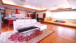 A modern living room with a white sofa, a coffee table, and a red rug. - Hotel Kaiho Shishinomori (Ishigaki)