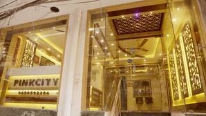 A hotel entrance with a glass facade, a visible staircase, and a sign reading "PINKCITY". - Hotel Pink City (New Delhi)