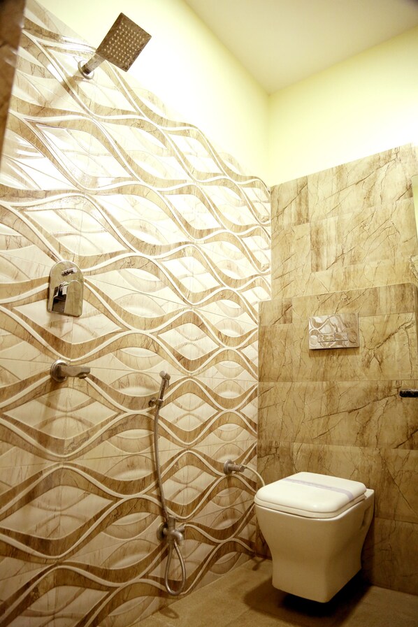 Un baño con pared de mármol, ducha e inodoro.