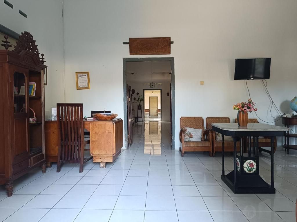 A spacious living area with a wooden cabinet, a television mounted on the wall, and a dining table with chairs.