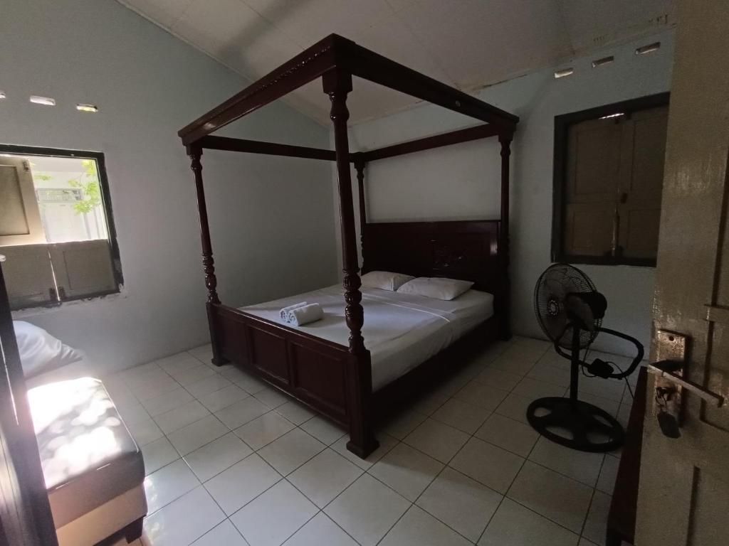 A room with a four-poster bed, a bedside fan, and a window with a view.