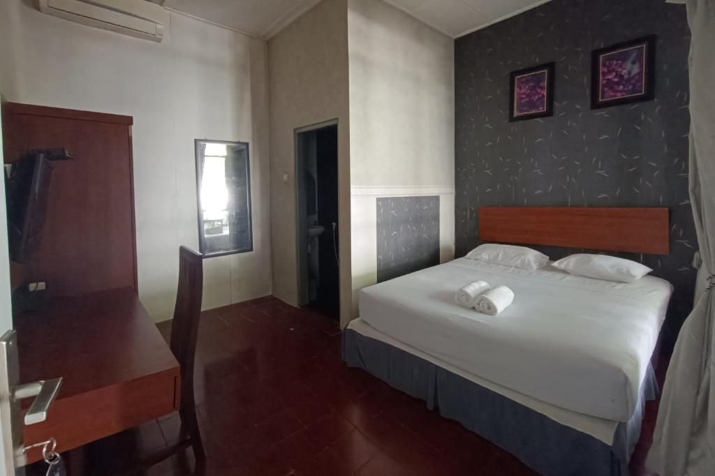 A hotel room with a bed, a desk, a chair, and a window.
