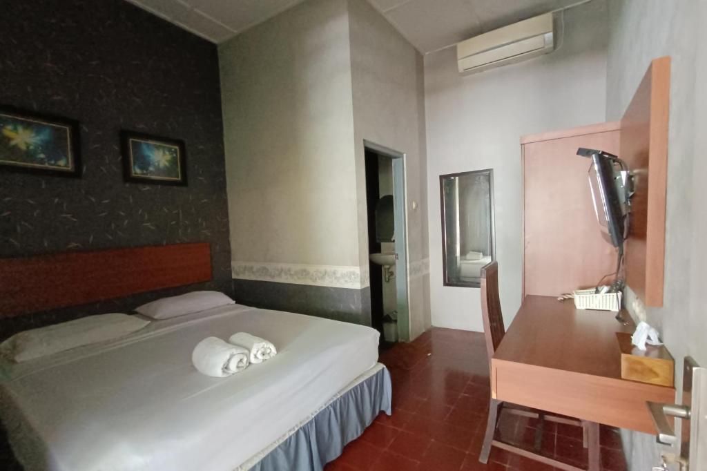 A hotel room with a bed, a desk, a mirror, and a bathroom door.