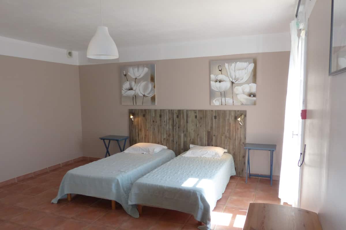 Une chambre avec deux lits, une tête de lit en bois et des œuvres d’art accrochées aux murs.