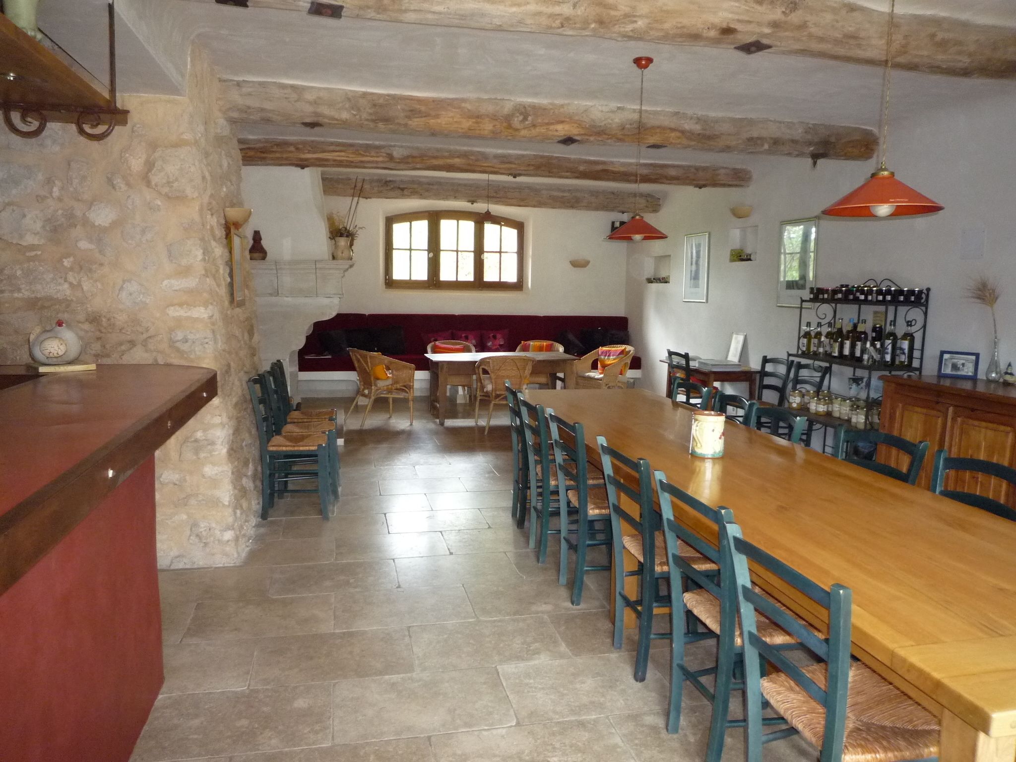A dining area with a long wooden table, several chairs, a stone wall, and a bar area with bottles.