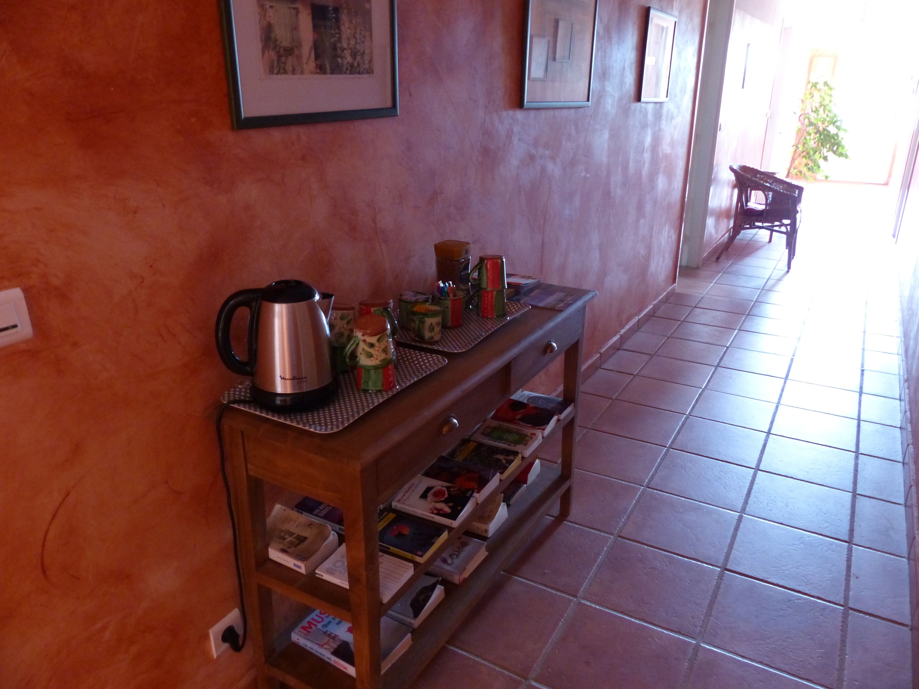 A hallway with a wooden console table holding a kettle, mugs, and books.