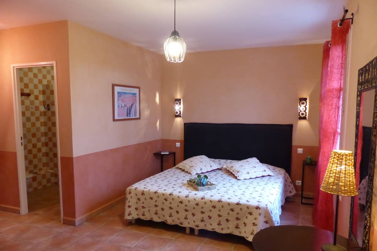 Une chambre à coucher comprenant un lit, une table de chevet, une chaise, un luminaire suspendu et une lampe fixée au mur.
